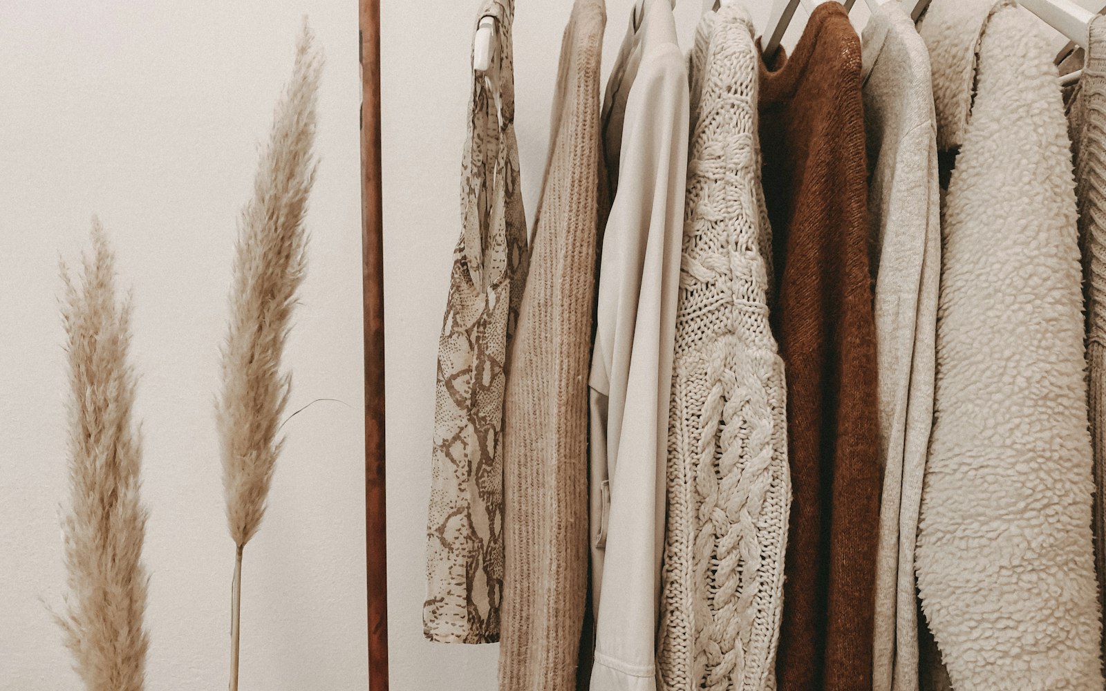 A rack of dresses and blouses pulled to one side of a boutique with a fitting room curtain open