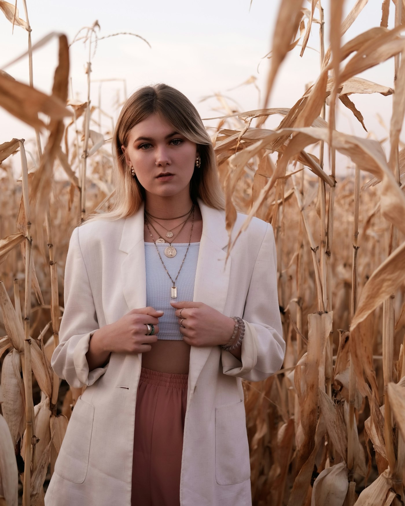 Cream linen blazer worn open over a pale blue ribbed tank, with layered gold necklaces and small gold hoops